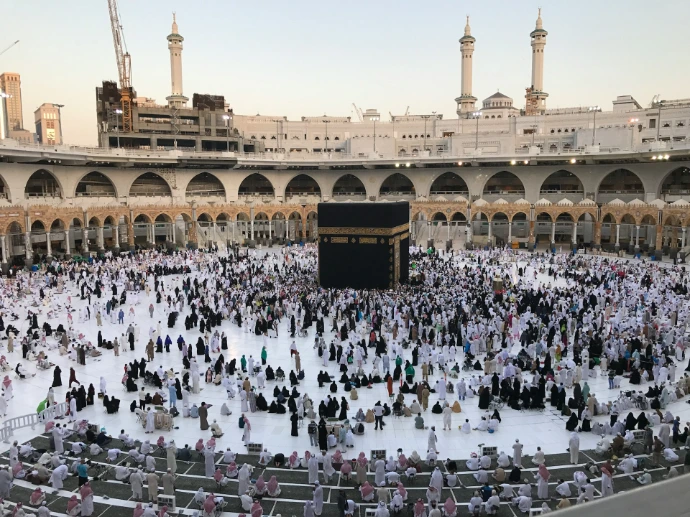 A large crowd of people surrounding the Kaaba in the Masjid al-Haram in Mecca